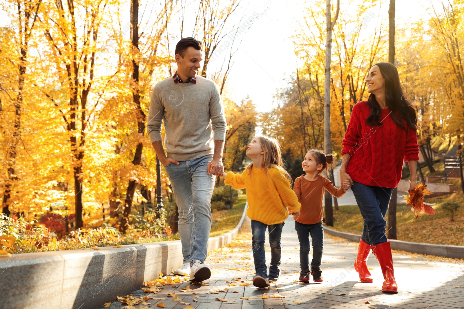 Photo of Happy family with little daughters walking in autumn park
