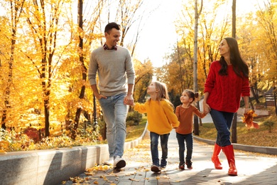 Happy family with little daughters walking in autumn park