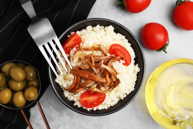 Photo of Tasty couscous with mushrooms and tomatoes served on grey table, flat lay