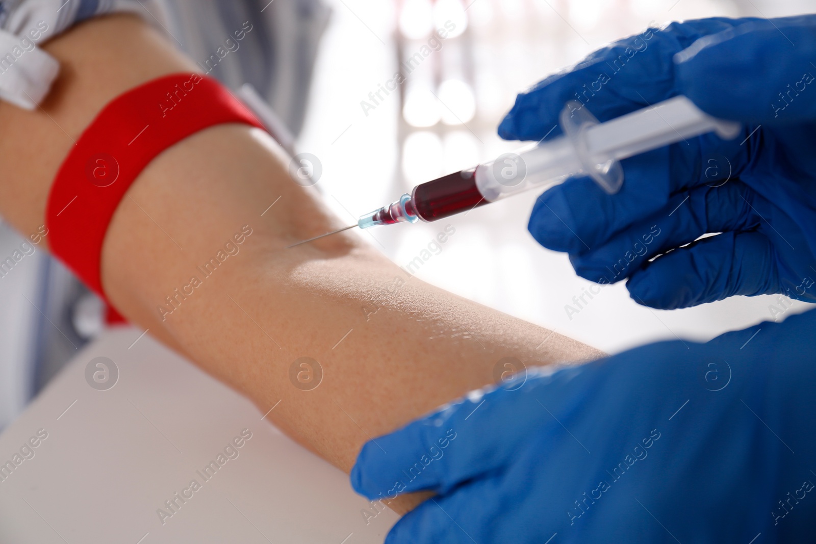 Photo of Nurse drawing blood sample from patient in clinic, closeup