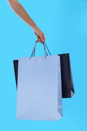 Photo of Woman with paper shopping bags on light blue background, closeup