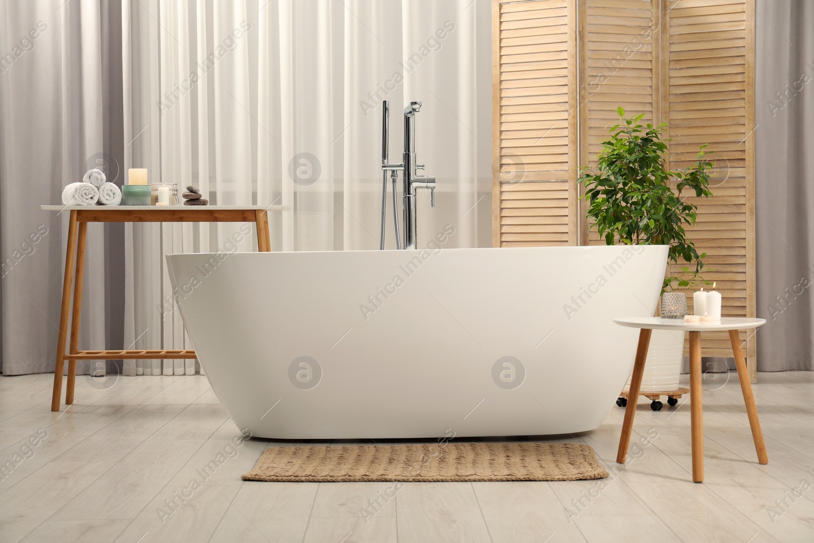 Photo of Ceramic tub, houseplant and spa products in bathroom