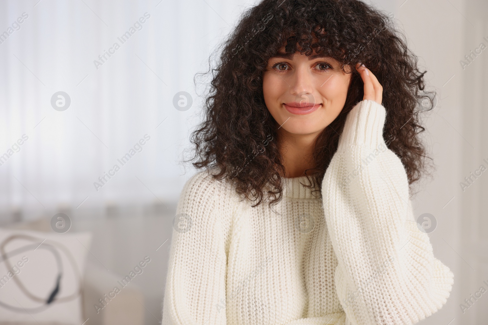 Photo of Young woman in stylish white sweater indoors, space for text