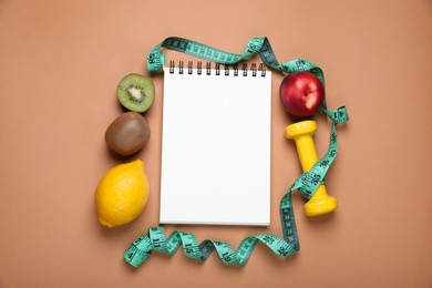 Photo of Measuring tape, notebook, dumbbell and fresh fruits on light brown background, flat lay. Low glycemic index diet