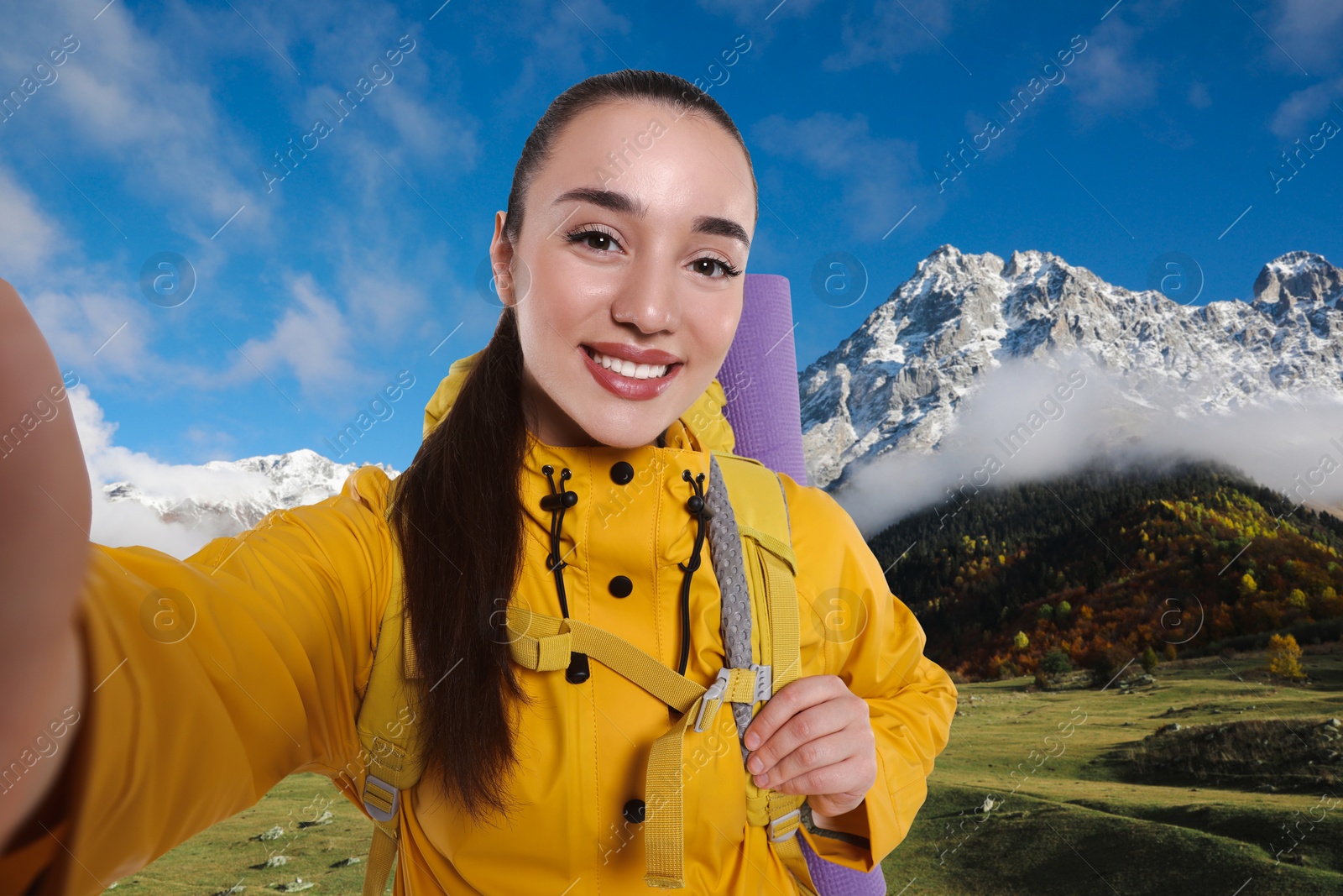 Image of Happy tourist with backpack taking selfie in mountains