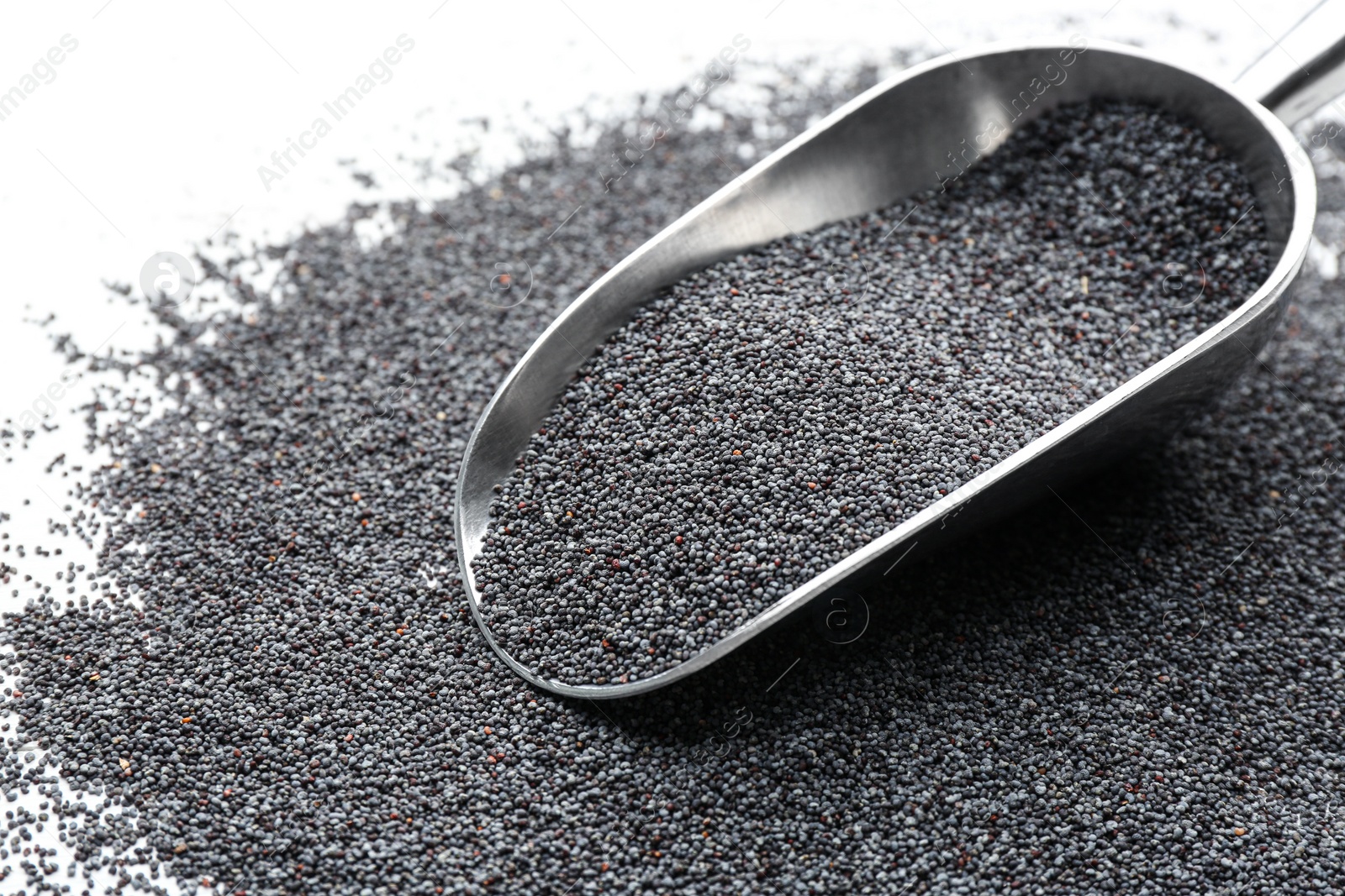 Photo of Poppy seeds and metal scoop on white table, closeup