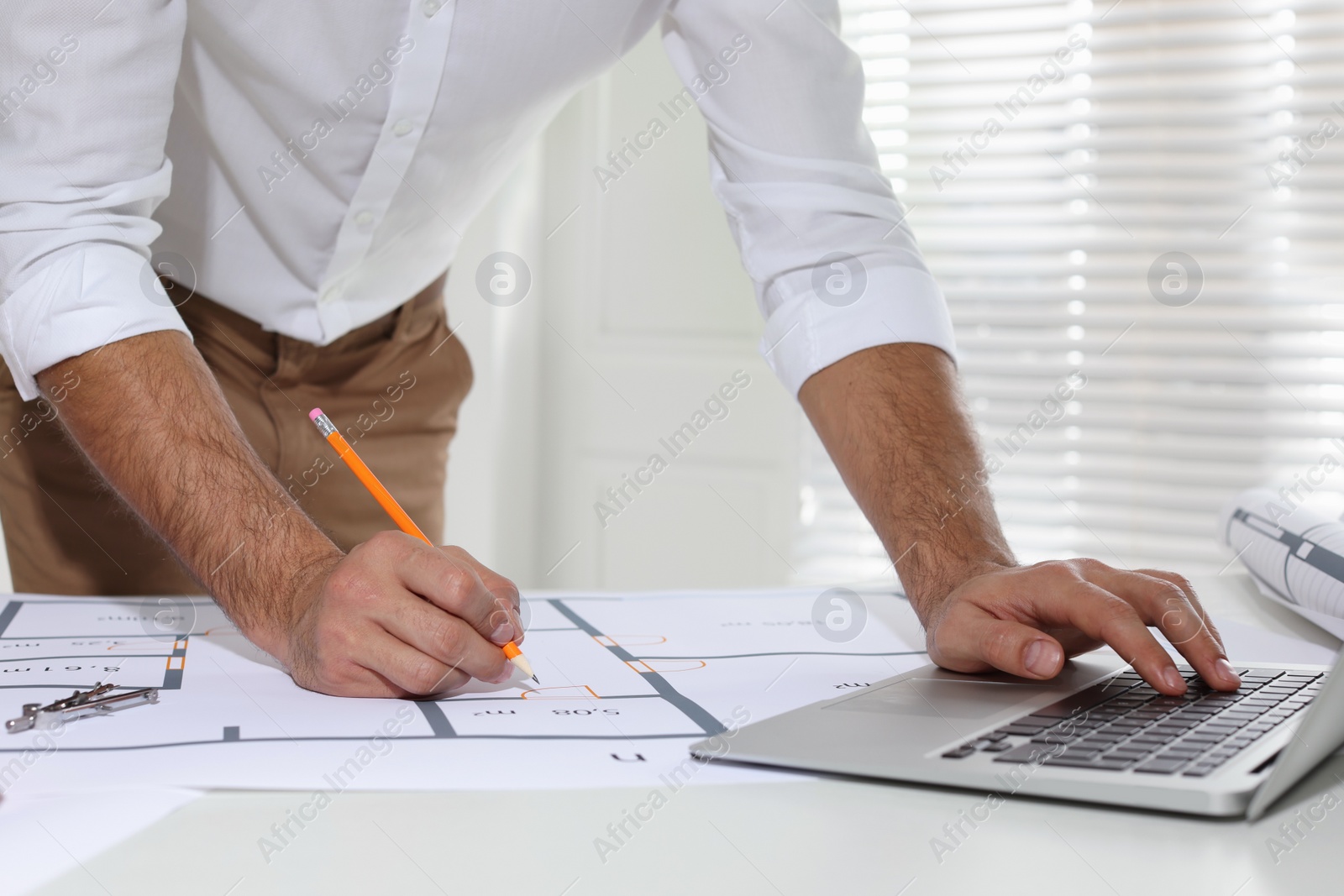 Photo of Architect working with construction drawings in office, closeup