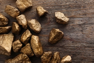 Photo of Pile of gold nuggets on wooden background, flat lay