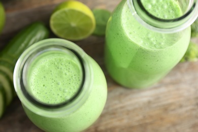 Photo of Bottles with healthy detox smoothie on table, closeup