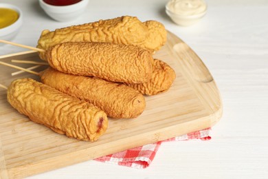 Photo of Delicious deep fried corn dogs on white wooden table