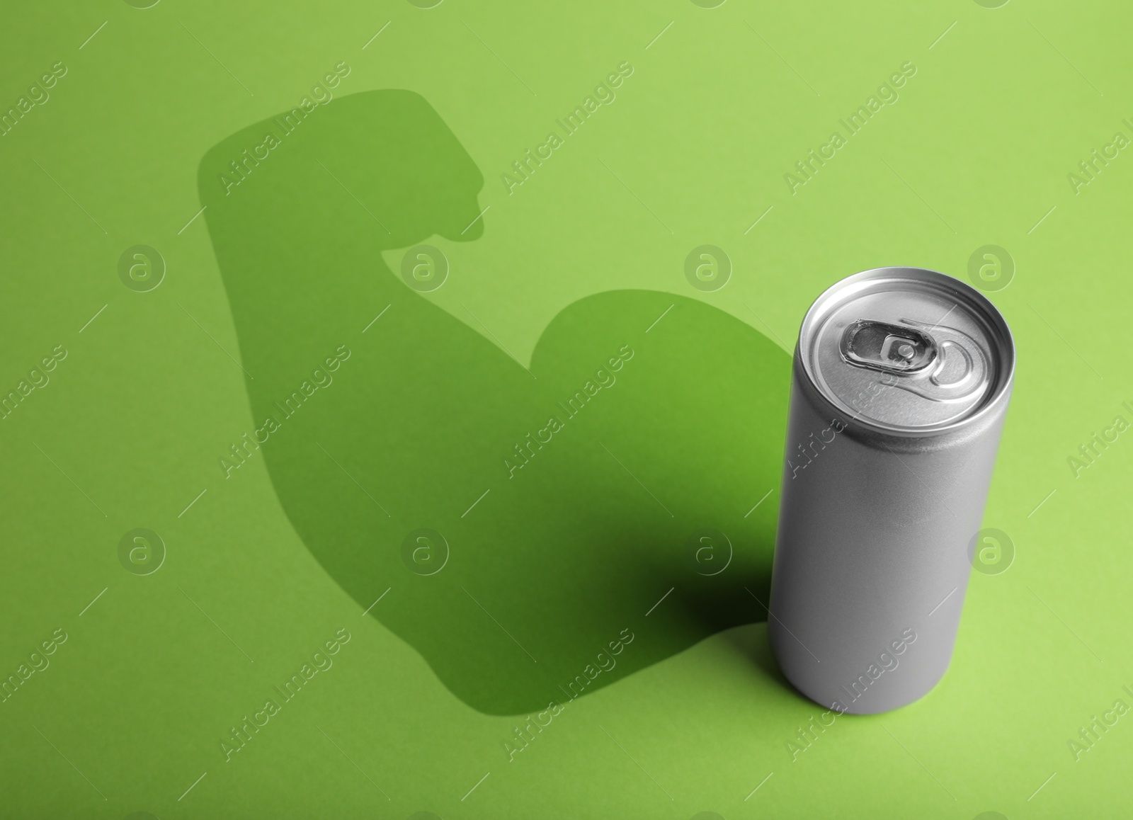 Image of Energy drink and shadow in shape of sportsman's hand silhouette on light green background 