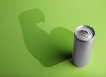 Image of Energy drink and shadow in shape of sportsman's hand silhouette on light green background 