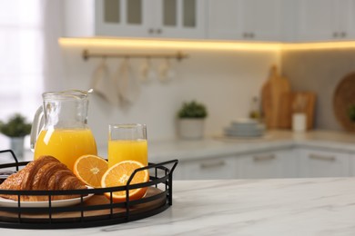 Photo of Breakfast served in kitchen. Tray with fresh croissant, jam and orange juice on white table, space for text