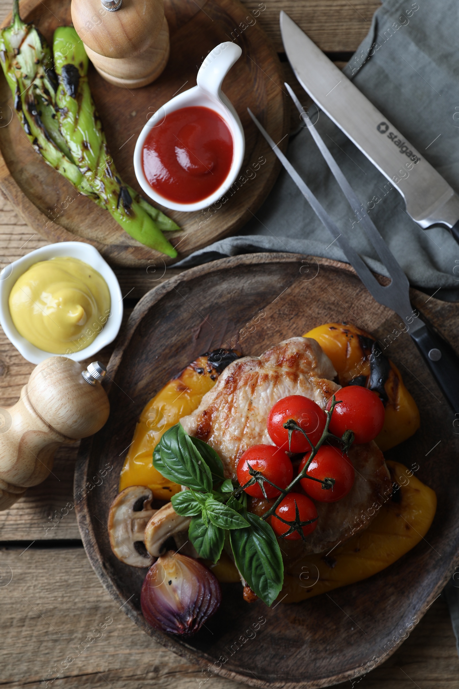 Photo of Delicious grilled meat and vegetables served with sauces on wooden table, flat lay