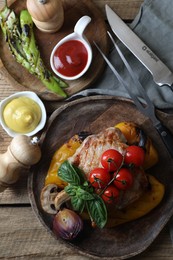 Delicious grilled meat and vegetables served with sauces on wooden table, flat lay