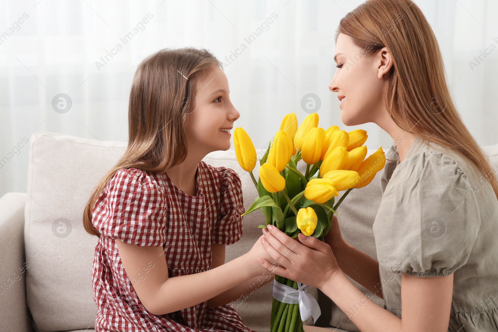 Photo of Daughter congratulating mom with bouquet of yellow tulips at home