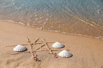Photo of Playing Tic tac toe game with shells on sand near sea