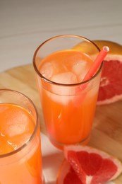 Photo of Tasty freshly made grapefruit juice and fruit on table, closeup