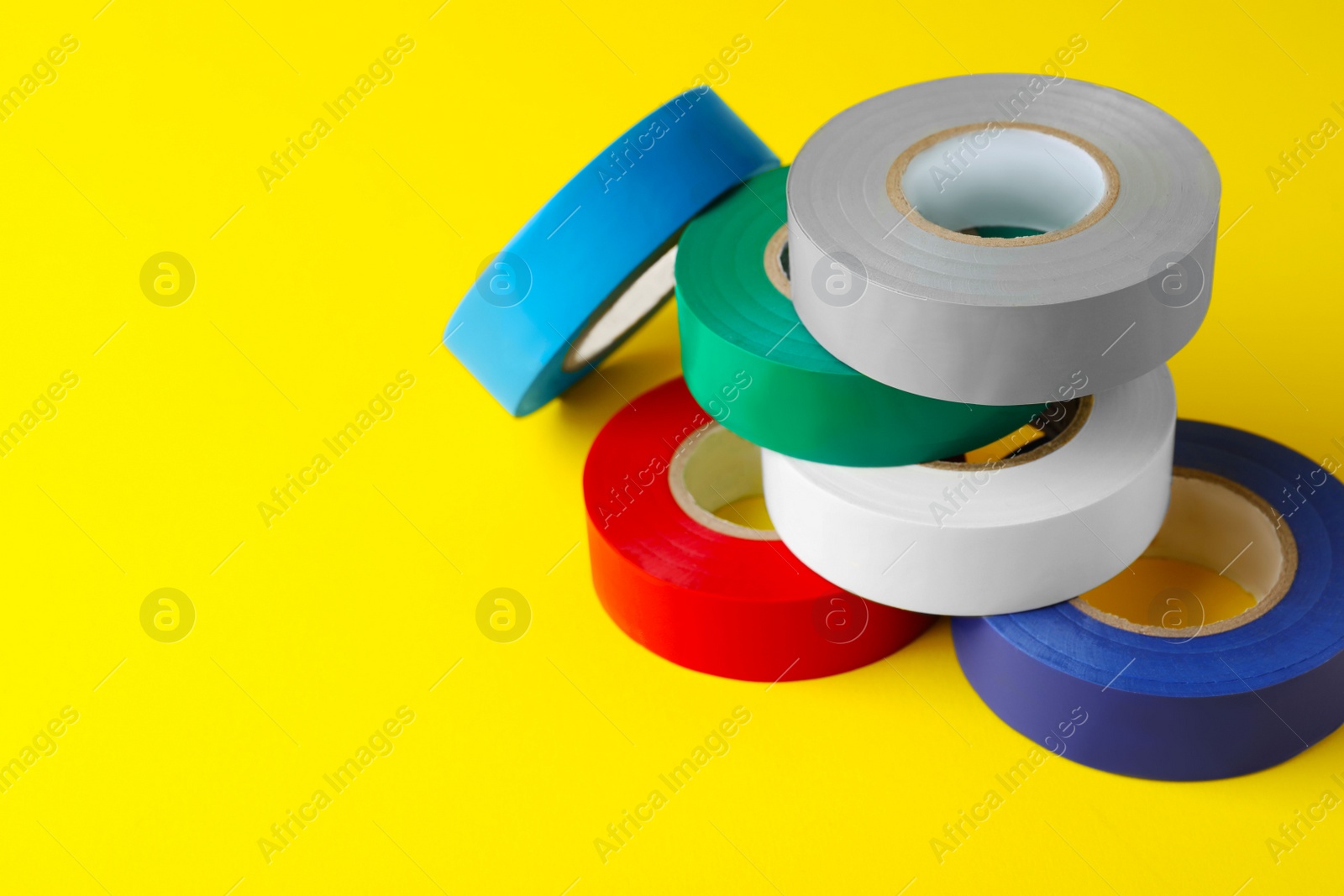 Photo of Colorful insulating tapes on yellow background. Space for text