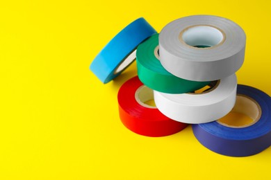 Colorful insulating tapes on yellow background. Space for text