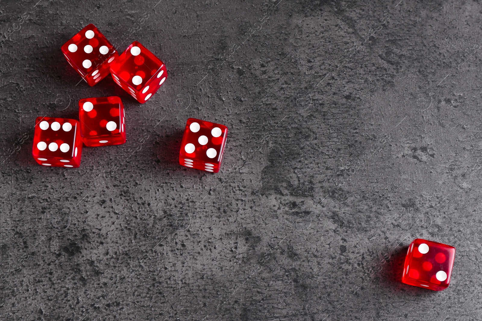 Photo of Many red game dices on grey textured table, flat lay