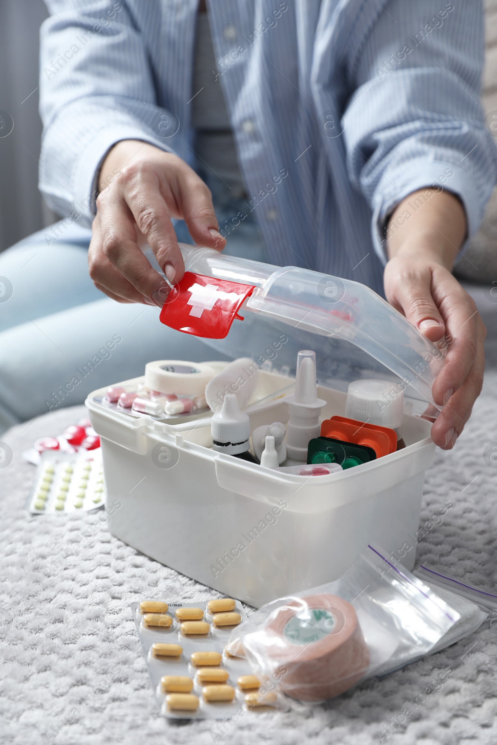 Photo of Woman opening first aid kit indoors, closeup