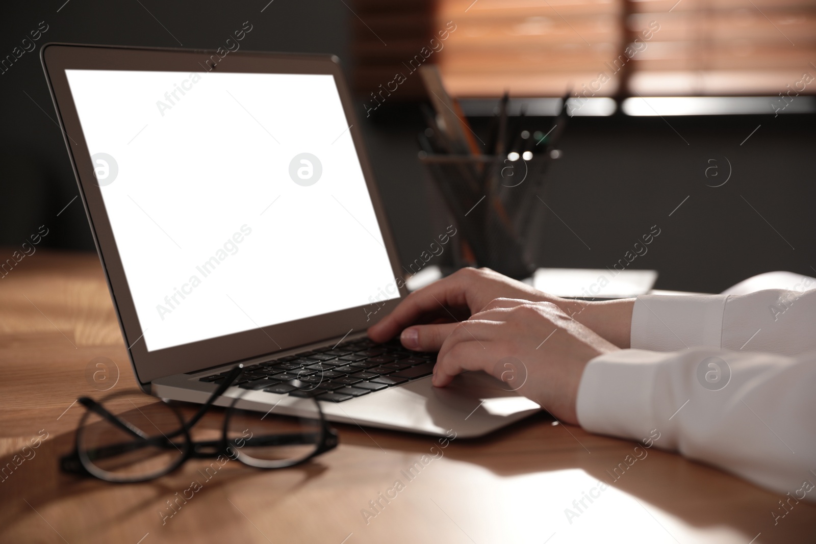 Photo of Woman working with laptop at wooden desk indoors, closeup