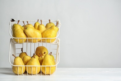 Photo of Basket of fresh ripe pears on table against light background with space for text