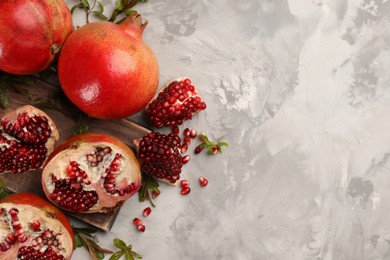 Photo of Delicious ripe pomegranates on grey table, flat lay. Space for text