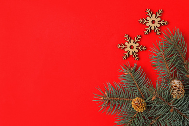 Photo of Christmas flat lay composition with fir branches on red background, space for text. Winter holidays