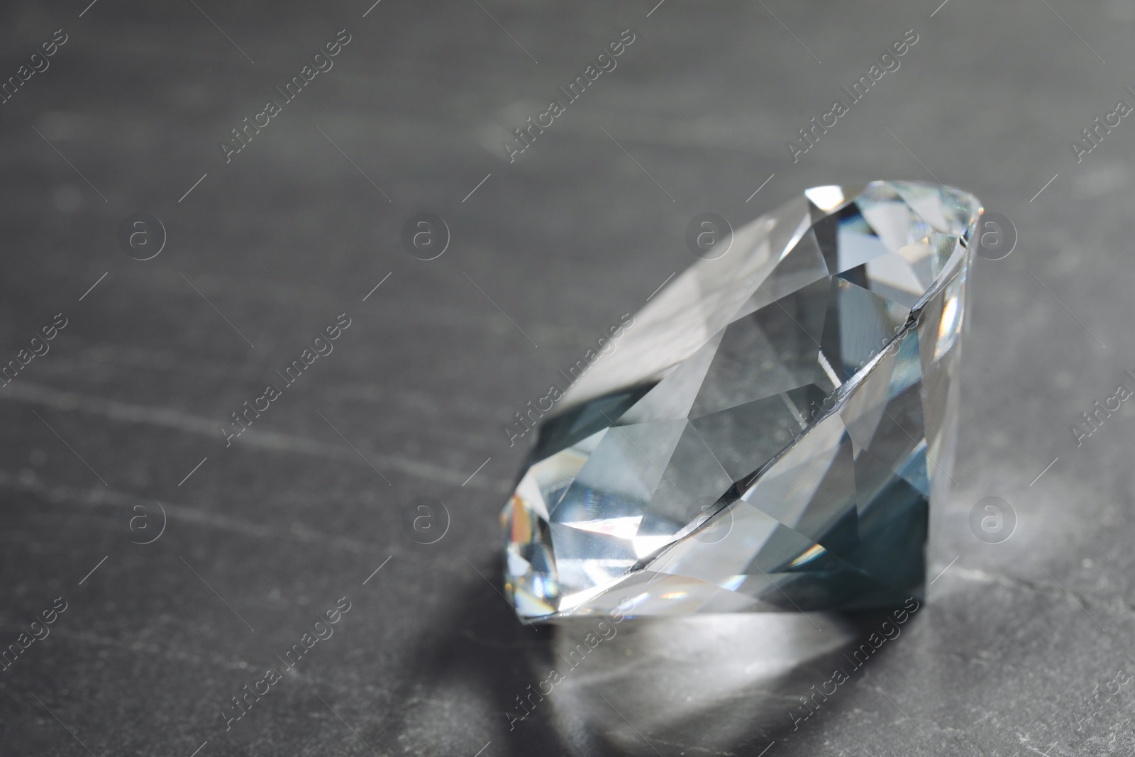 Photo of Beautiful dazzling diamond on black textured background, closeup. Space for text