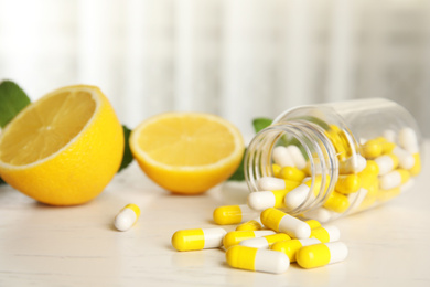 Bottle with vitamin pills and lemon on light table
