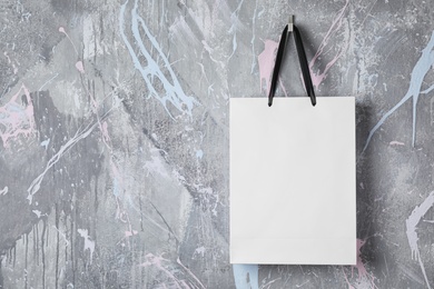 Paper shopping bag with handles hanging on color wall. Mock up for design