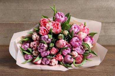 Photo of Bouquet of beautiful tulips on wooden table