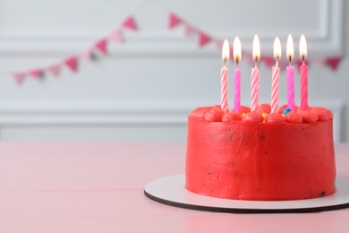 Cute bento cake with tasty cream and burning candles on pink wooden table. Space for text