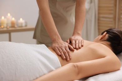 Photo of Woman receiving back massage on couch in spa salon