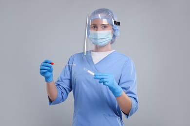 Photo of Laboratory testing. Doctor with cotton swab and tube on light grey background