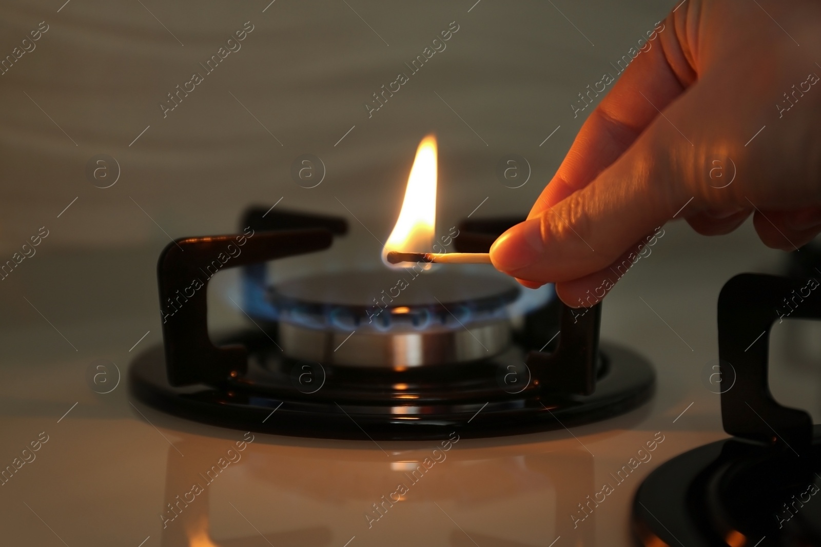 Photo of Woman lighting gas stove with match, closeup