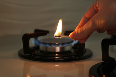 Photo of Woman lighting gas stove with match, closeup