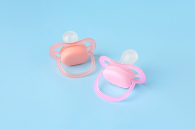 Photo of Two new baby pacifiers on light blue background