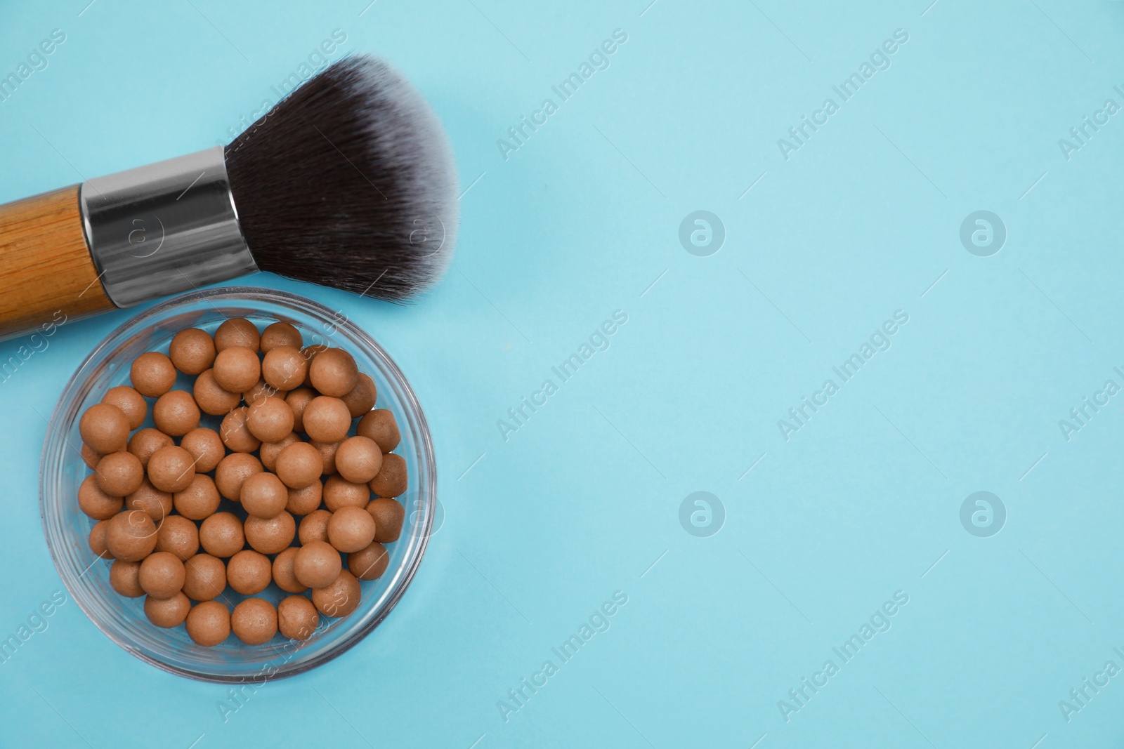 Photo of Face powder balls and brush on light blue background, flat lay. Space for tex
