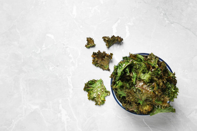 Tasty baked kale chips on grey marble table, flat lay. Space for text