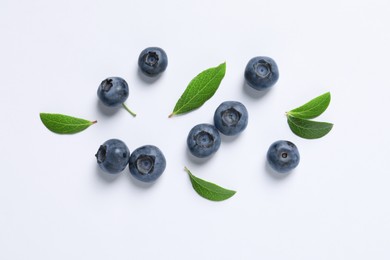 Tasty fresh blueberries with green leaves on white background, flat lay