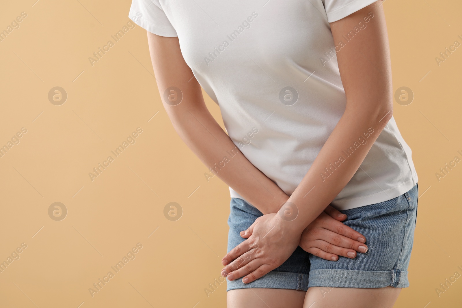 Photo of Woman suffering from cystitis on beige background, closeup. Space for text