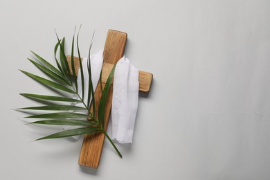 Photo of Wooden cross, white cloth and palm leaf on light grey background, top view with space for text. Easter attributes