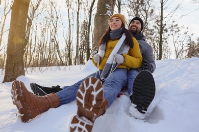 Photo of Happy young couple sleighing outdoors on winter day, low angle view