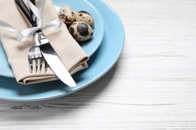 Festive Easter table setting with eggs on white wooden background, closeup. Space for text