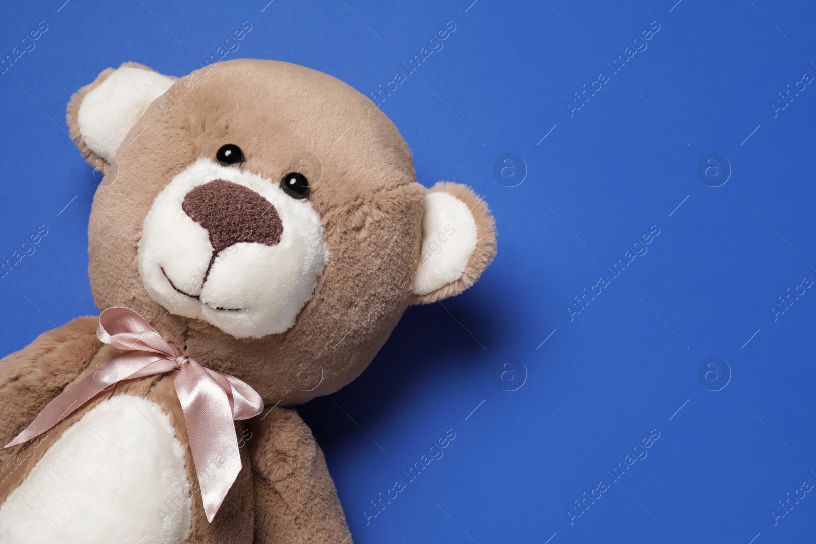 Photo of Cute teddy bear on blue background, top view. Space for text