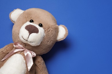 Photo of Cute teddy bear on blue background, top view. Space for text