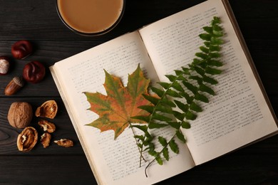 Flat lay composition of book with autumn leaves as bookmark on wooden table